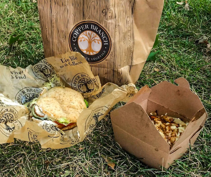 Copper Branch bag and food picnic style on the grass. Featuring gluten free poutine/vegan poutine. Eating Gluten Free in Montreal.