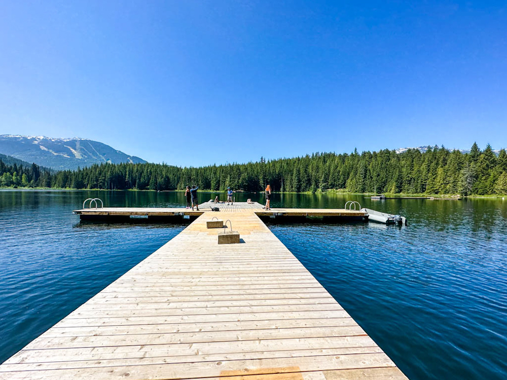 A view of a long dock ending in the blue waters of Lost Lake in Whistler, British Colombia, Canada