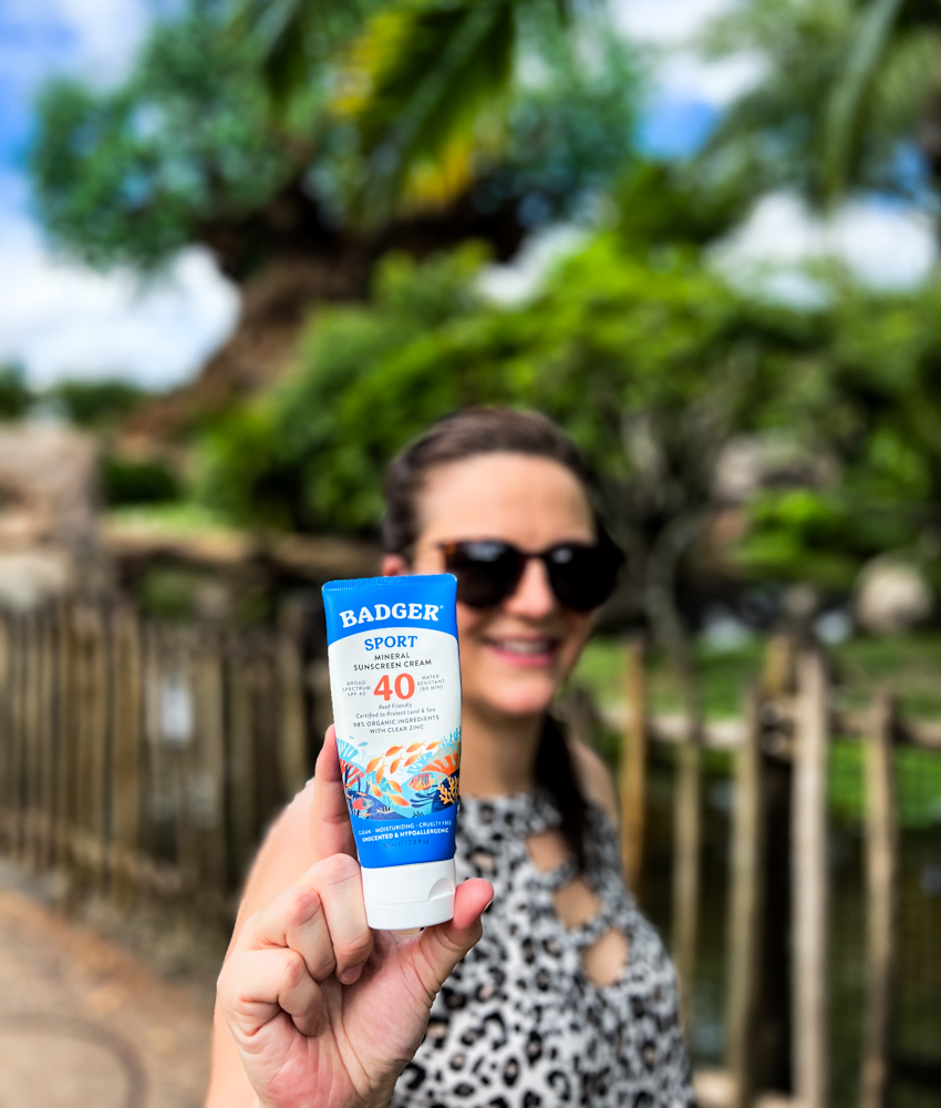 Badger Sport Sunscreen with the blurred background of me holding it in front of the tree of life at Disney's Animal Kingdom