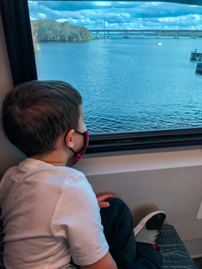 kid looking out the window of a train to a river