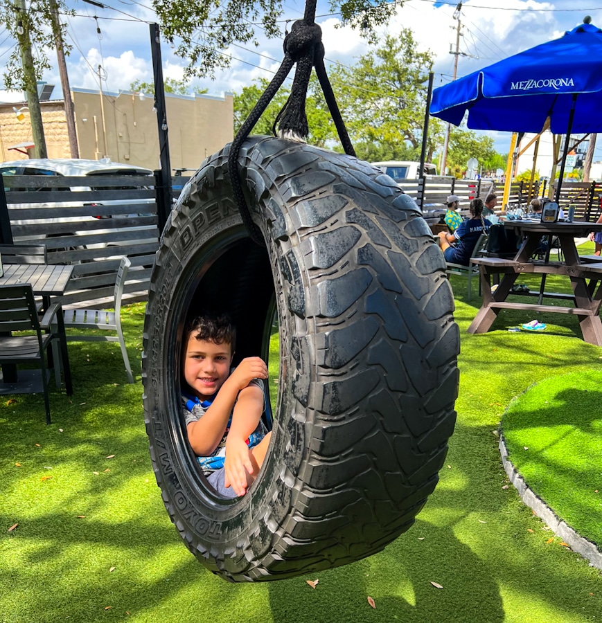 little boy sitting in a tire swing at a restaurant