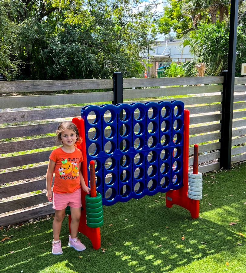little girl standing in front of a life size connect 4