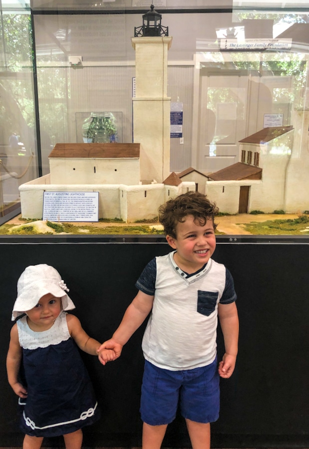 2 small children in front of a replica of the first St Augustine Lighthouse at the Lighthouse Museum in St Augustine Florida