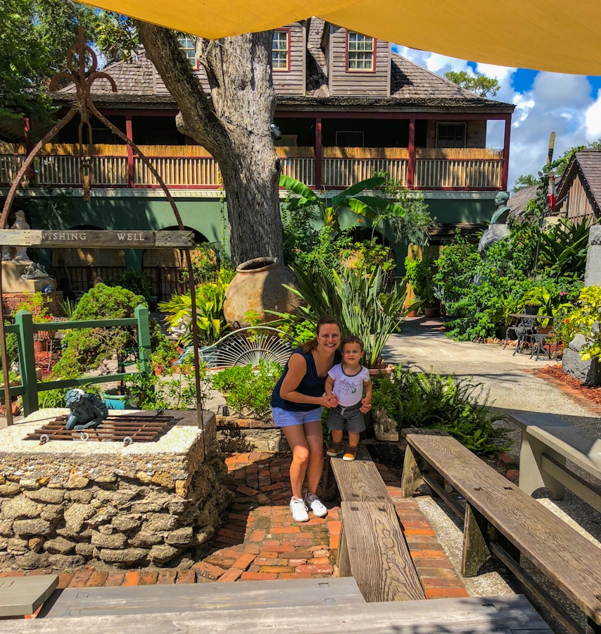 parent and child standing in the garden area and wishing well of the Oldest Schoolhouse Museum in St Augustine Florida