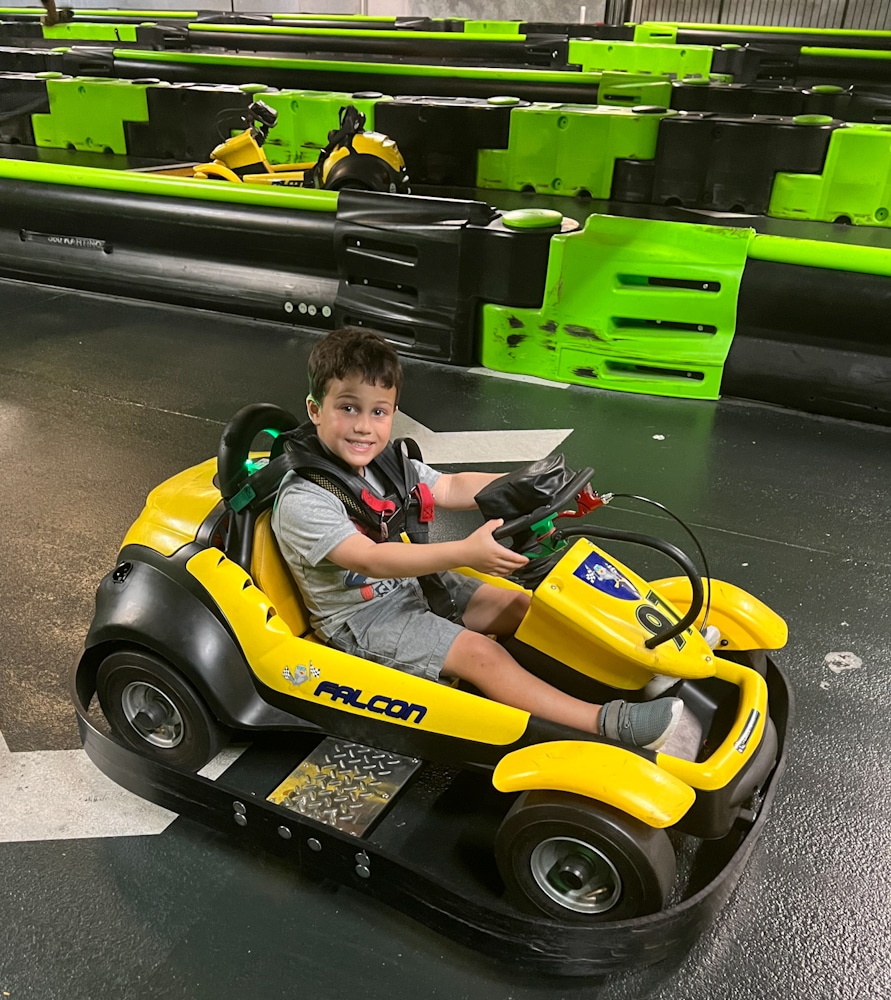 little boy in a yellow go kart driving around the track