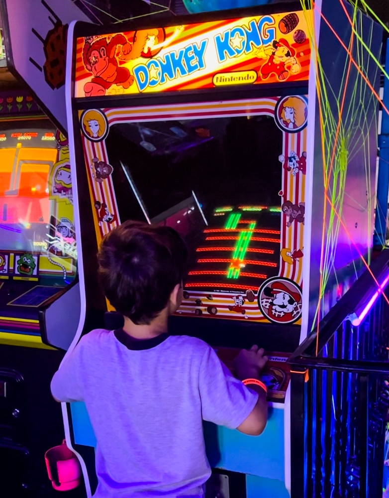 young boy playing Donkey Kong arcade game