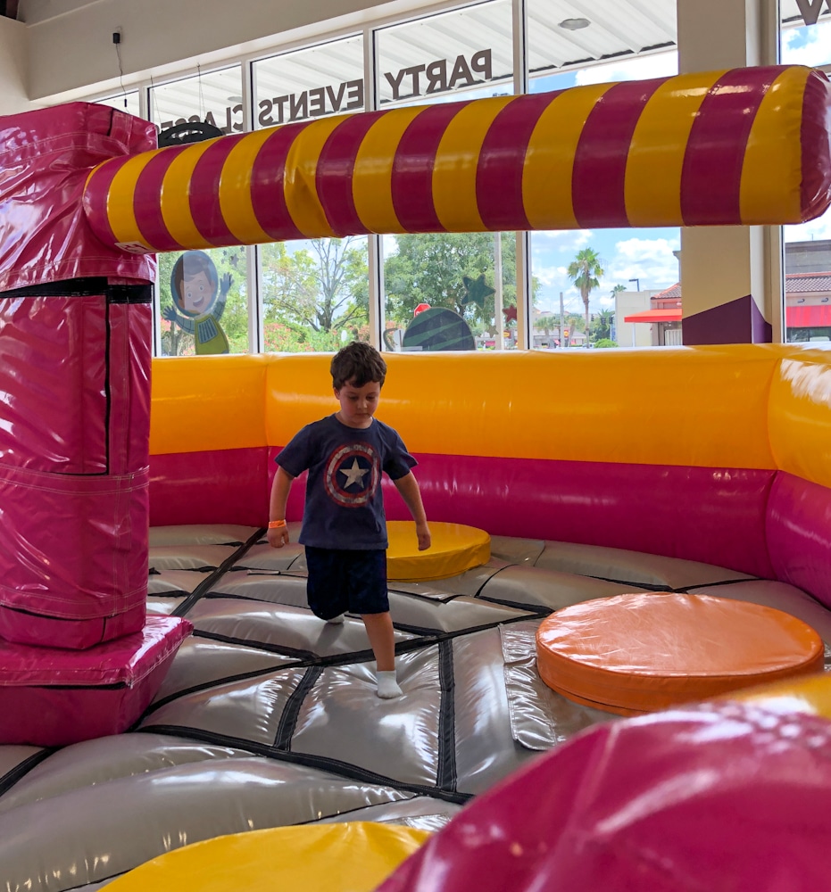 little boy jumping on a bounce house rotating arm