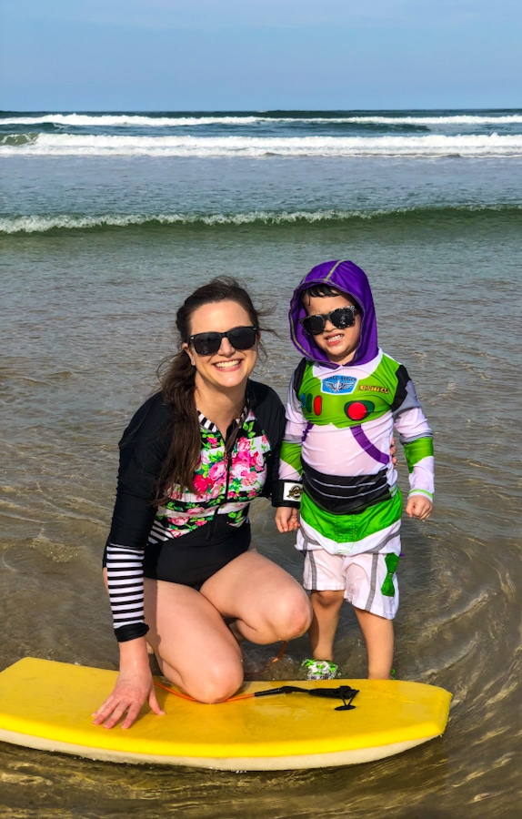 mother and son at the beach leaning on a yellow boogie board